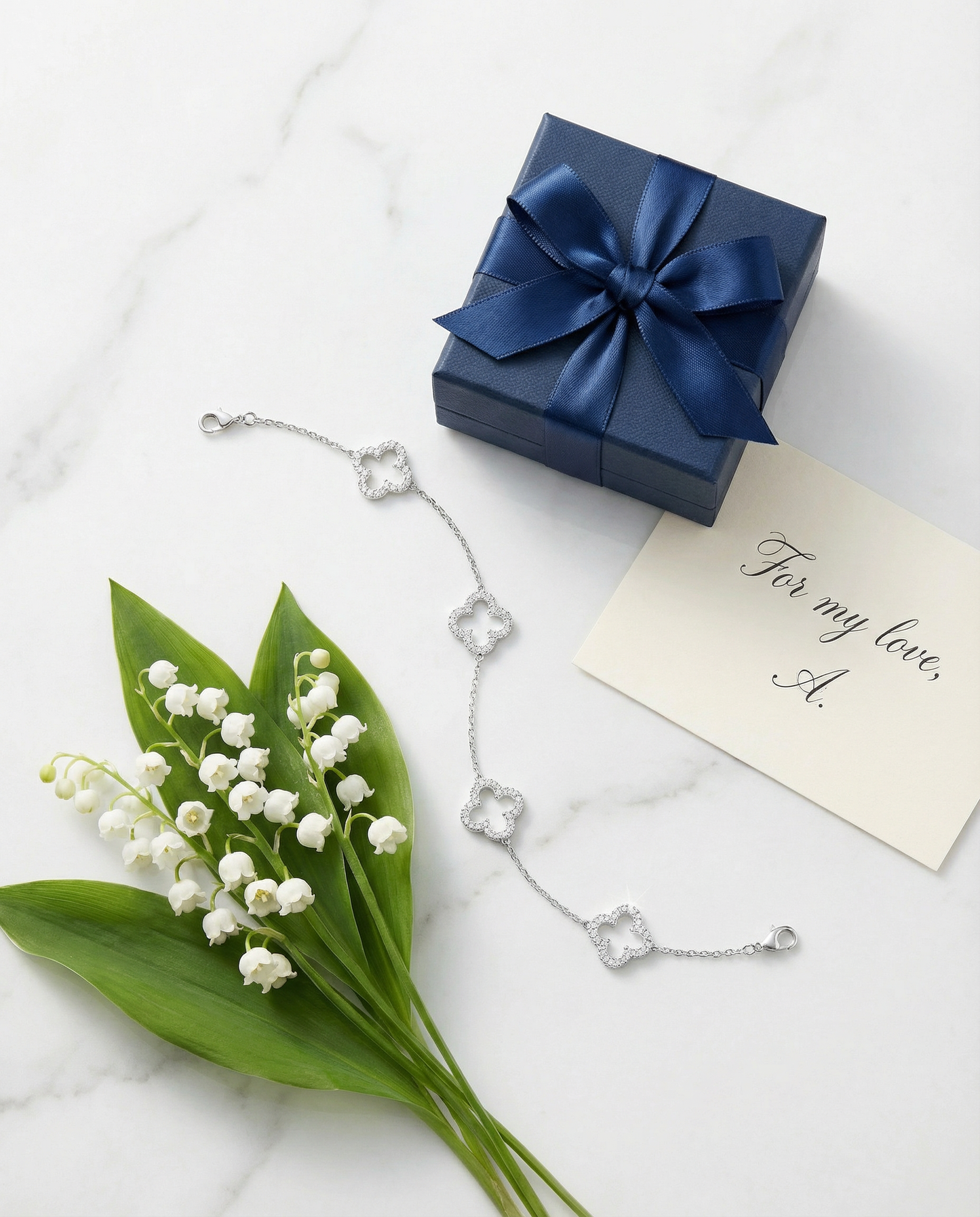Clover Bracelet — White marble flat lay with navy gift box and lily of the valley